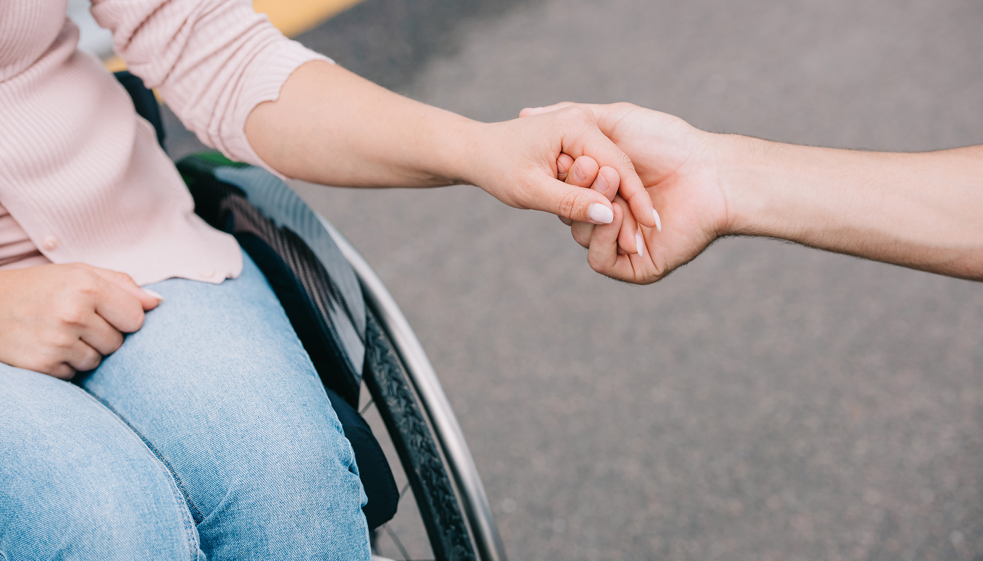 Person on wheelchair holding hand