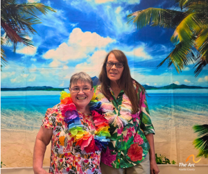 Two ladies posing together in front of beach backdrop
