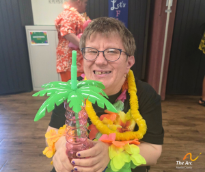 A smiling Adult Taining Facility (ATF) participant holding her cup.