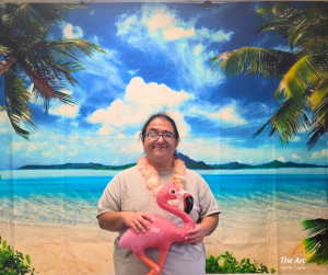 Guy posing with inflatible flamingo in front of beach backdrop