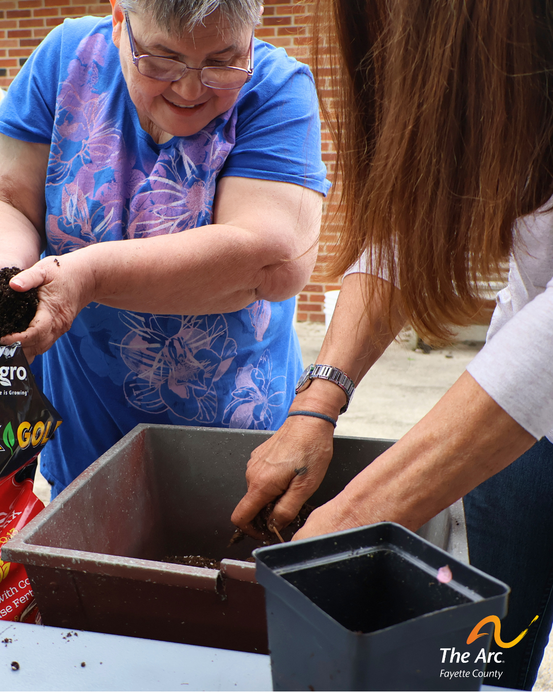 Adult Training Facility (ATF) participant moving soil while planting tomatoes.