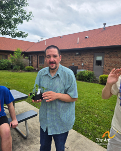 A smiling Adult Taining Facility (ATF) participant holding one of the plants.